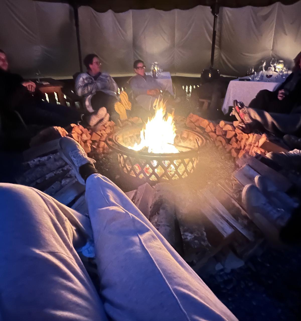 Guests wrapped in blankets around a lit fire pit at a BALA evening experience.